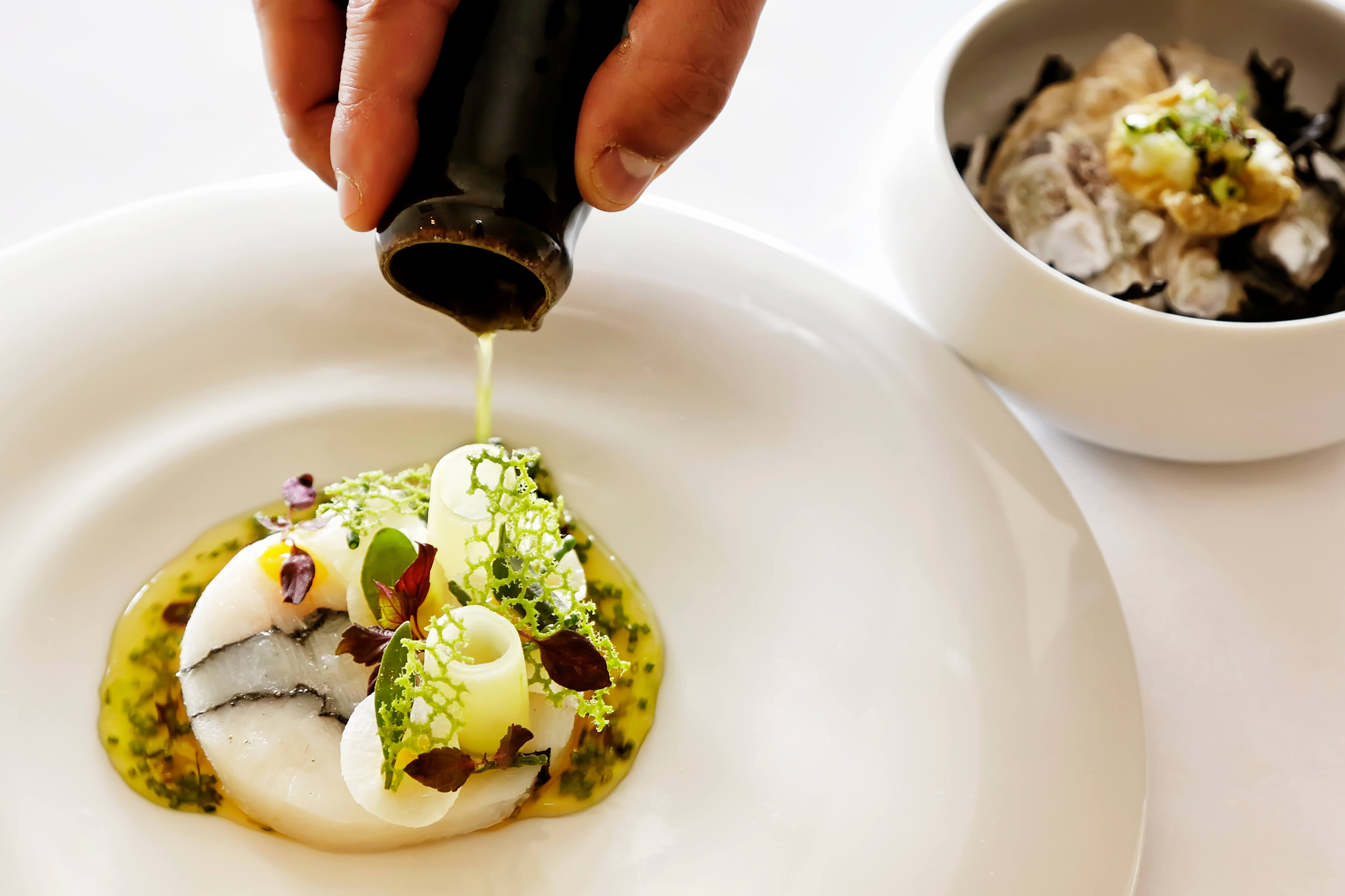 A delicate meal prepared by Chris Eden being drizzles with oil ready to be served at the Driftwood Hotel